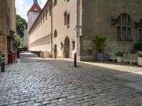 a street with a bench in the middle of the walkway, and a building in the distance