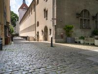 a street with a bench in the middle of the walkway, and a building in the distance