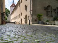 a street with a bench in the middle of the walkway, and a building in the distance