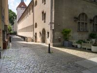 a street with a bench in the middle of the walkway, and a building in the distance