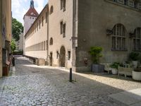 a street with a bench in the middle of the walkway, and a building in the distance