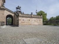 a statue on a horse near a building and walkways with stone paving in the foreground