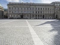 people in front of a building with cobblestones and buildings in the background,