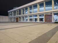 an empty courtyard is lit up by windows at night time with no people in it