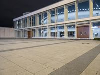 an empty courtyard is lit up by windows at night time with no people in it