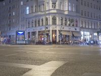 a city intersection has traffic passing by a tall building at night time in europe on a dark stormy day