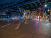 the empty street is filled with people walking and biking under an overpass at night