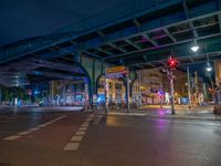 the empty street is filled with people walking and biking under an overpass at night