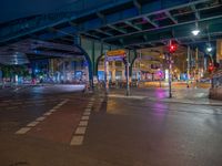 the empty street is filled with people walking and biking under an overpass at night