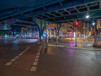 the empty street is filled with people walking and biking under an overpass at night