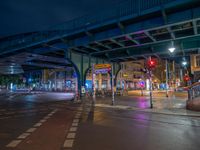 the empty street is filled with people walking and biking under an overpass at night