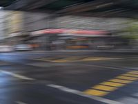 an image of a blurry picture of a city street with a street sign on the corner