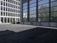 two people walk through an empty parking lot near large building with many windows on both sides of the street