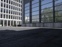 two people walk through an empty parking lot near large building with many windows on both sides of the street