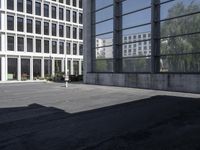 two people walk through an empty parking lot near large building with many windows on both sides of the street