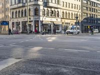 people walk down the street as traffic lights turn on the corner of a city street