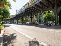 an overpass is an extension to an overpass on the street on which cars are parked on a narrow street with trees and buildings in the background