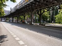 an overpass is an extension to an overpass on the street on which cars are parked on a narrow street with trees and buildings in the background