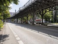 an overpass is an extension to an overpass on the street on which cars are parked on a narrow street with trees and buildings in the background