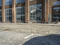 a person is sitting on the sidewalk looking down at a bench in front of a building