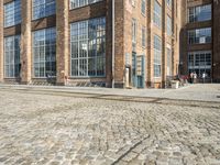 a person is sitting on the sidewalk looking down at a bench in front of a building