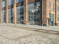 a person is sitting on the sidewalk looking down at a bench in front of a building