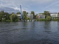 several apartment buildings on the edge of a body of water with trees and building in the background