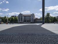 a wide outdoor walkway with pavement and buildings in the background with people walking around it