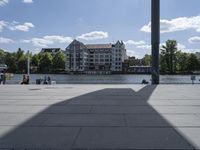 a wide outdoor walkway with pavement and buildings in the background with people walking around it