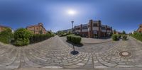 the fisheye lens photo shows an old town scene with brick streets and parked cars