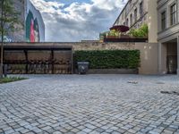 an empty parking lot with plants in the ground and on the side of the building, there is an enclosed area and windows