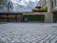 an empty parking lot with plants in the ground and on the side of the building, there is an enclosed area and windows