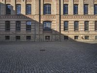 a group of large buildings with several windows and doors are standing on the cobblestones
