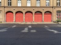 a row of red fire garages next to an empty road with white lines in it