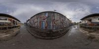 a fisheye lens image of several boats on the water and buildings in the background