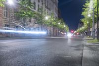 a dark street lit by street lights at night time with long exposure of traffic in a city