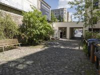 there is a stone walkway that leads into a building with several plants and benches beside it