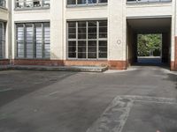 a parking lot near a building with windows and a no parking sign outside the building