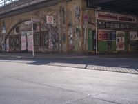 a man crossing a road that has been covered with graffitti on it and posters above it