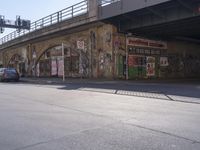 a man crossing a road that has been covered with graffitti on it and posters above it