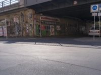 a man crossing a road that has been covered with graffitti on it and posters above it