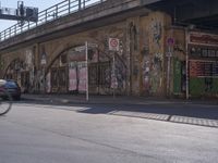 a man crossing a road that has been covered with graffitti on it and posters above it