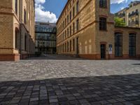 a sidewalk with chairs next to the brick building on the side, some have stairs and some buildings in the background