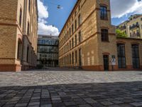 a sidewalk with chairs next to the brick building on the side, some have stairs and some buildings in the background