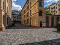 a sidewalk with chairs next to the brick building on the side, some have stairs and some buildings in the background