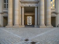 a courtyard with a building on the other side and a large white building with many windows