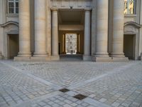 a courtyard with a building on the other side and a large white building with many windows