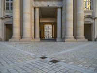 a courtyard with a building on the other side and a large white building with many windows