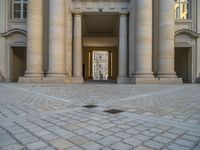 a courtyard with a building on the other side and a large white building with many windows