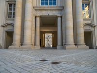 a courtyard with a building on the other side and a large white building with many windows